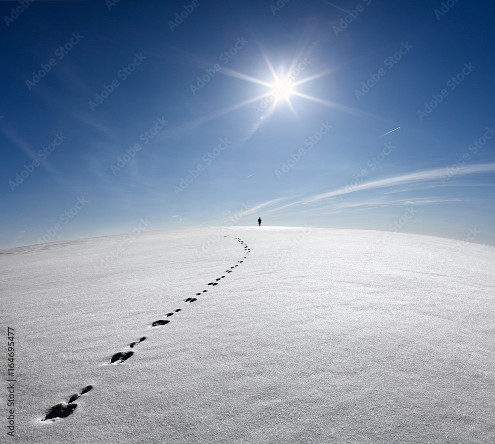 Man,Earth,Universe. Lonely Man Walking On Snow Crust Field On The Trail Of Hare At The Background Of The Sun And Flying Plane. Abstract Photo Silhouette Of A Man On The Road In Winter Empty Field