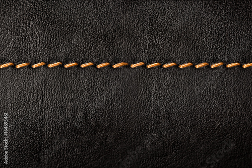 Black leather texture background with orange seams