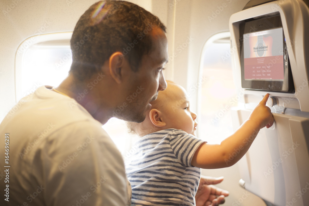 Father and son playing with a screen on airplane
