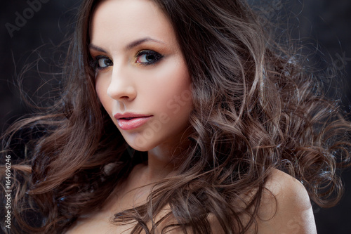 Brunette girl with long wavy hair . Beautiful model with curly hairstyle