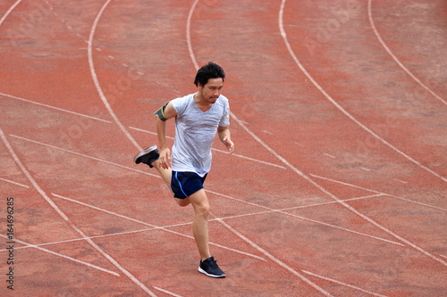 Athlete Asian man running on racetrack in stadium. Healthy active lifestyle concept.