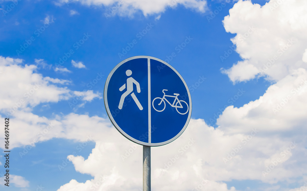 Round, blue sign of a walkway for bicycles and pedestrians on a cloudy background Round, blue sign of a walkway for bicycles and pedestrians on a cloudy background