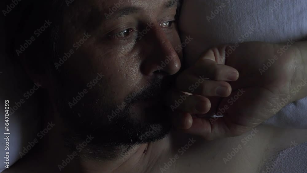 Morning depression and midlife crisis of a man in his 40s lying in bed in morning with symptoms like extreme sadness, frustration, anger and fatigue.