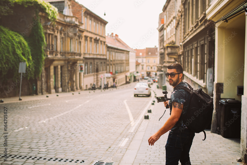 Male professional videographer travel photographer making video in 4K resolution trough the streets of Zagreb holding 3 axis gimbal stabilizer.Filming with stabilized camera.Travel light equipment