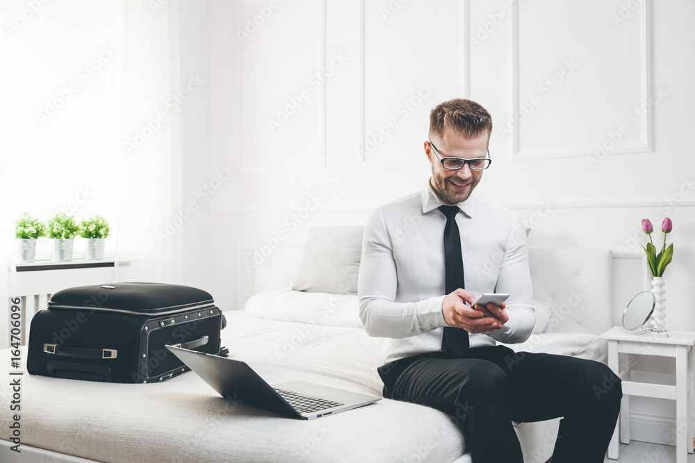 Businessman working from a hotel room with his mobile phone Businessman working from a hotel room with his mobile phone