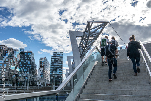 People walking over bridge to the business area at Bjørvika in Oslo, Norway with a modern Scandinavian architecture with glass windows