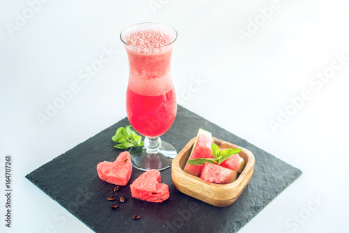 Fresh red smoothie in a glass with sliced pieces of watermelon and mint on white isolated background. Summer cool drinks
