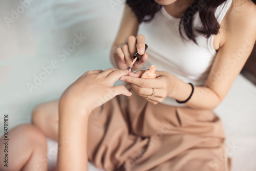 Close-up. Two young girlfriends polishing nails in living room at home.