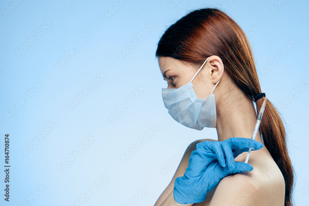 Young beautiful woman on a blue background holds a syringe, medicine, plastic surgery Young beautiful woman on a blue background holds a syringe, medicine, plastic surgery