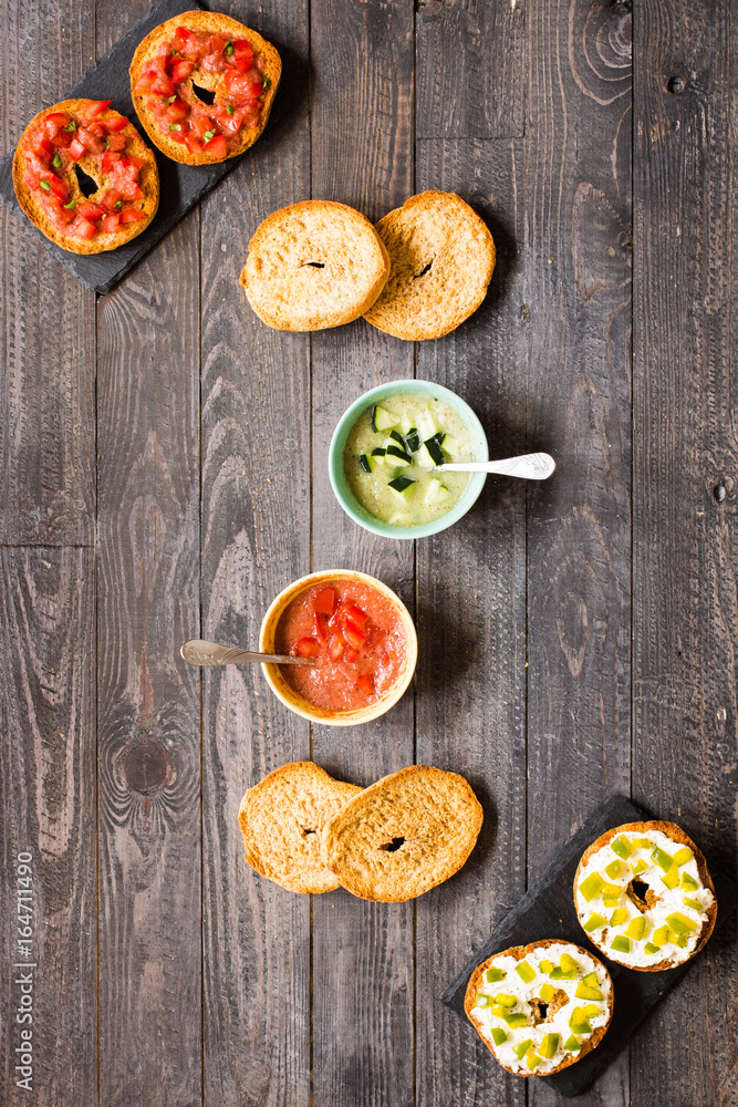 Italian bruschetta with cheese, tomato sauce, cucumber sauce, and herbs, on a wooden background.