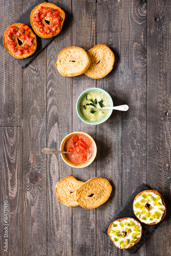Italian bruschetta with cheese, tomato sauce, cucumber sauce, and herbs, on a wooden background.