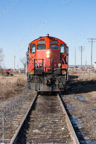 Head On View of Red Locomotive on Tracks in City