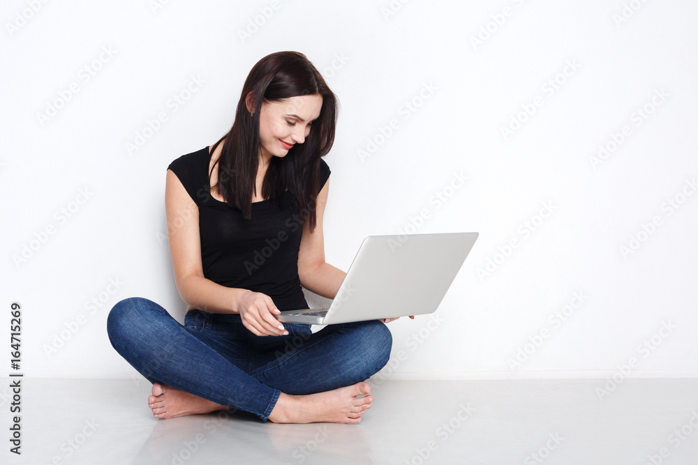 Woman using laptop sitting on the studio floor Woman using laptop sitting on the studio floor