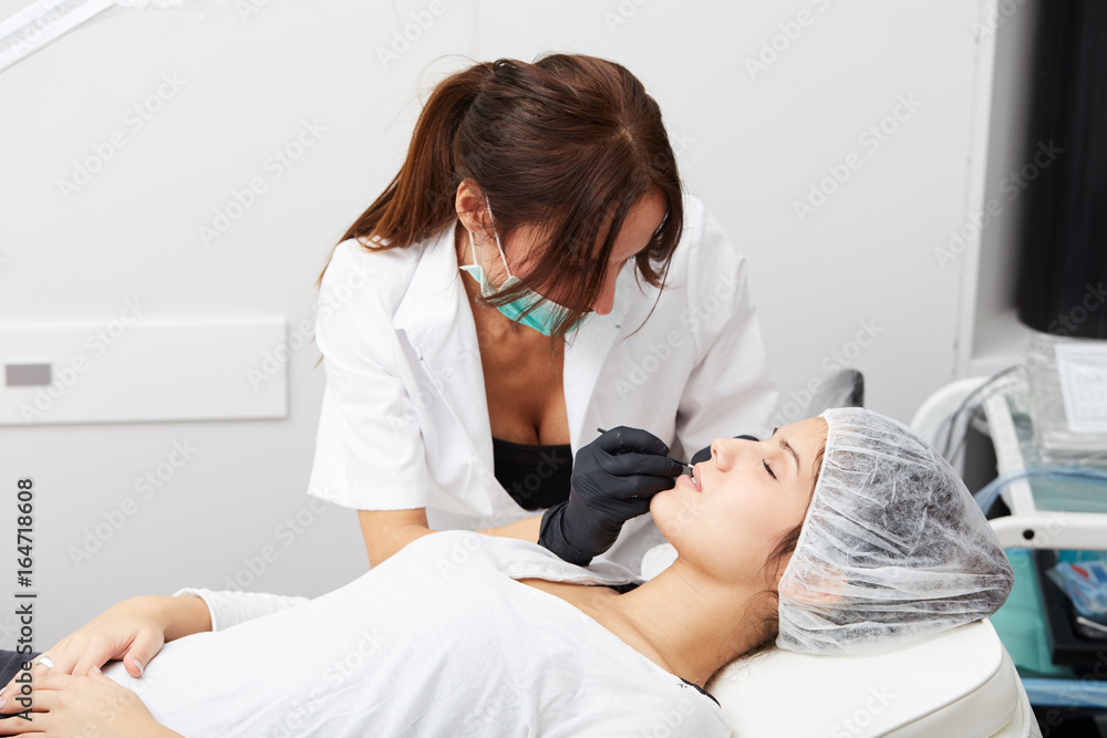 Obraz premium Cosmetologist making permanent makeup on woman's face