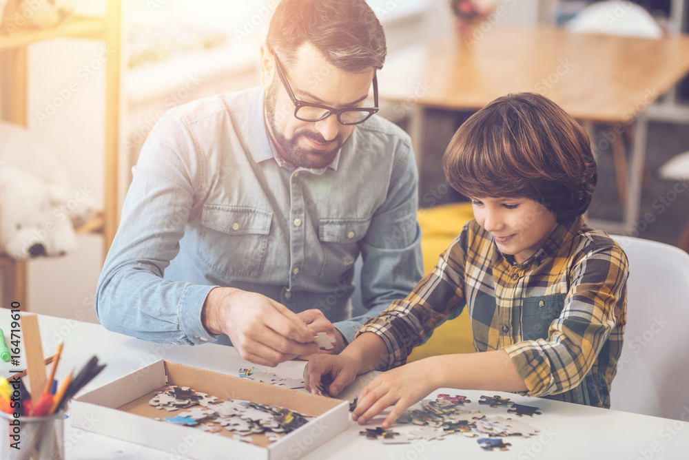 Fototapeta premium Positive nice man holding a jigsaw puzzle piece