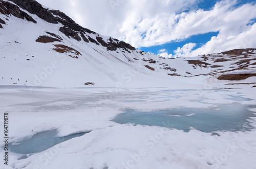 A landscape view from Hochtor tunnel on the Grossglockner high alpine road. Looking towards Heiligenblut in Carinthia with blue sky, mountains clouds and snow and the Grossglockner high alpine road. photo