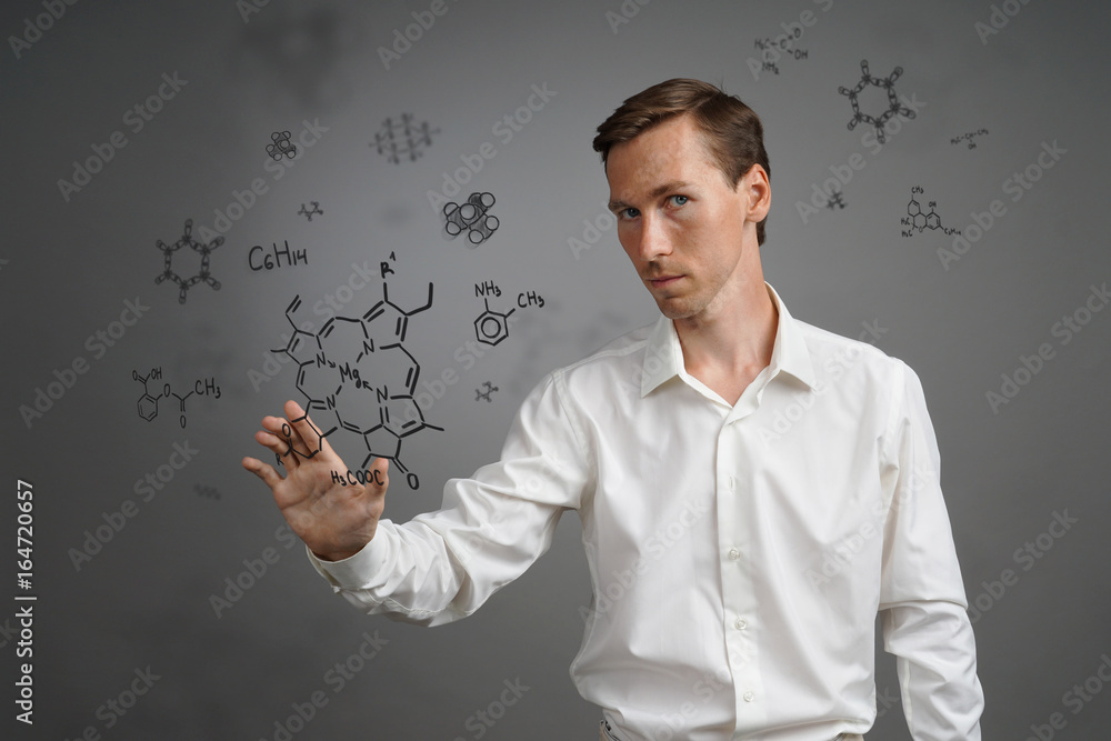 Man scientist in white shirt working with chemical formulas on gray background. Man scientist in white shirt working with chemical formulas on gray background.