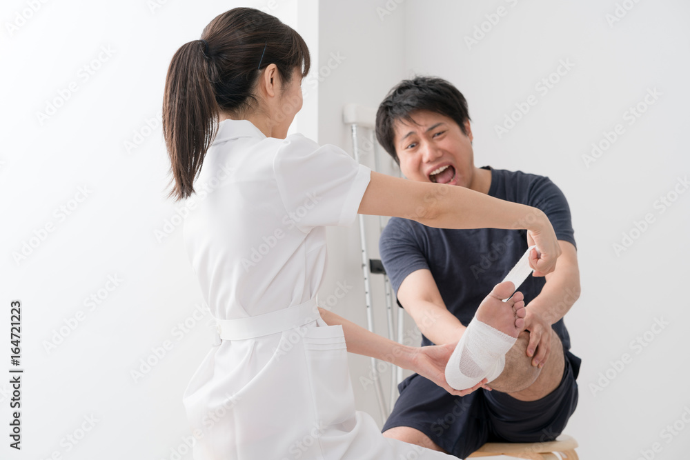 足に包帯を巻く看護師、患者 足に包帯を巻く看護師、患者