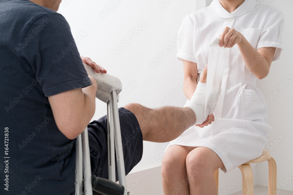 足に包帯を巻く看護師、患者 足に包帯を巻く看護師、患者