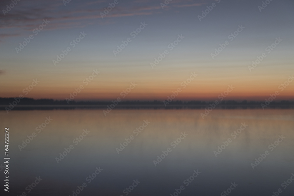 Sunrise with clouds and fog over lake
