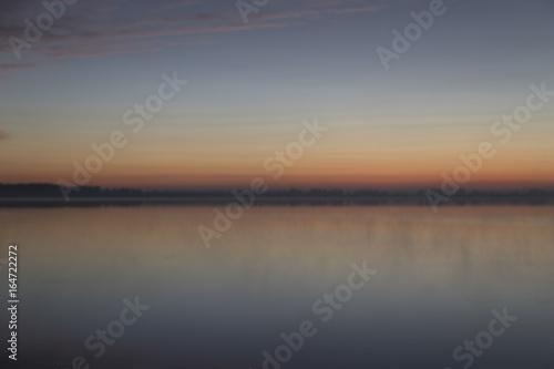 Sunrise with clouds and fog over lake