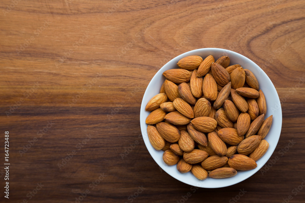 Almonds seed in white bowl on wooden table with copy space. Almonds seed in white bowl on wooden table with copy space.