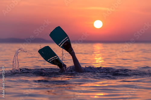 Diver with flippers at sunset over sea