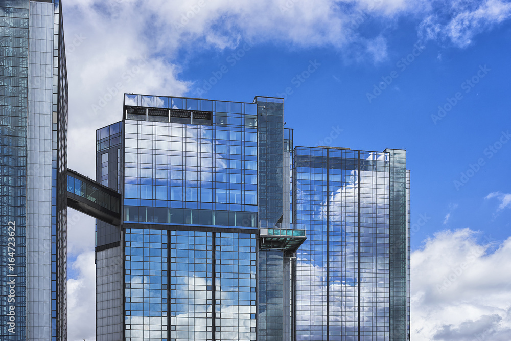 Modern glass building skyscrapers with blue cloudy sky reflection. Business district background.