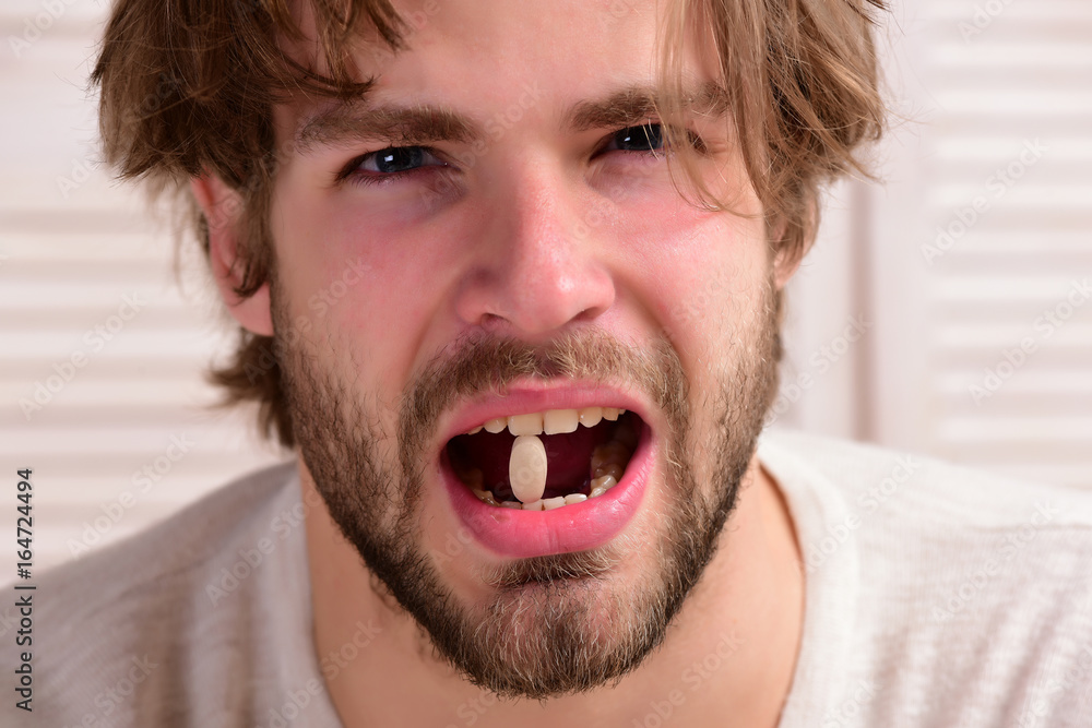 Patient with attentive face holds capsule in his teeth Patient with attentive face holds capsule in his teeth