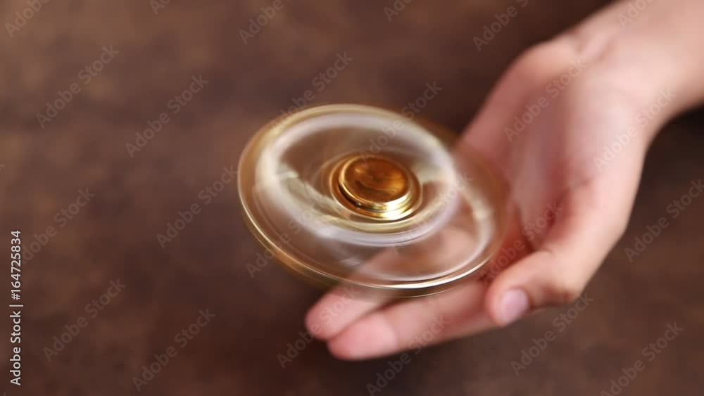 Little child playing with modern popular hand toy - spinner. Boy sitting on brown cozy sofa in home interior and rotating golden anti stress spinner on one finger. Real time full hd video footage. Little child playing with modern popular hand toy - spinner. Boy sitting on brown cozy sofa in home interior and rotating golden anti stress spinner on one finger. Real time full hd video footage.