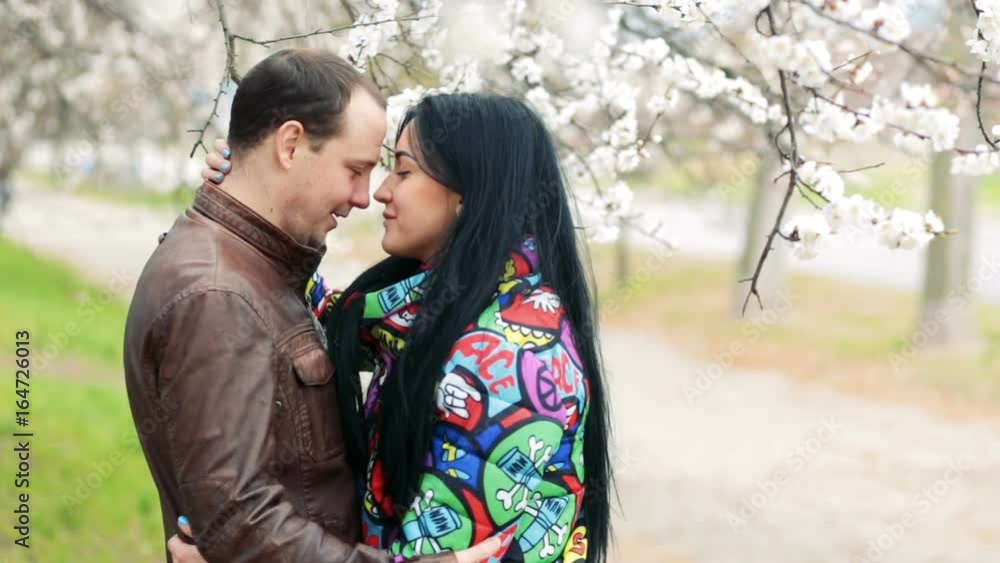 A pair of lovers hugging in a blooming garden A pair of lovers hugging in a blooming garden