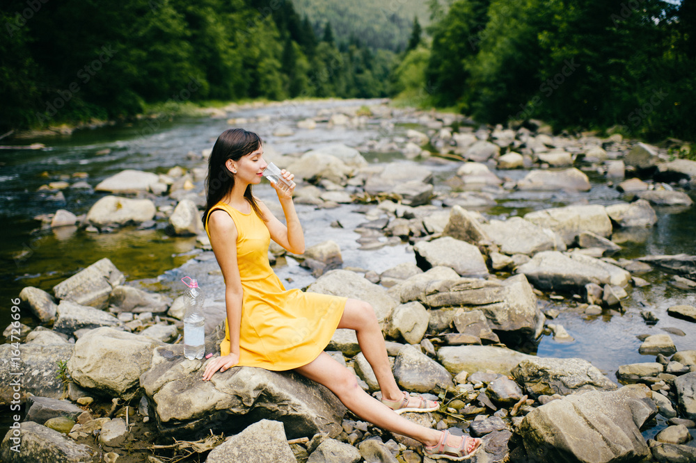 Travel in mountains. River with stones on shore. Heat temptation. Thirst suffer. Young girl drinking water. Satisfaction of wish. Eyes closed in peace and harmony. Rest in pleasure. Tired under sun Travel in mountains. River with stones on shore. Heat temptation. Thirst suffer. Young girl drinking water. Satisfaction of wish. Eyes closed in peace and harmony. Rest in pleasure. Tired under sun