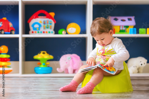 Quadro em tela Cute little baby girl,sitting on potty and reading.