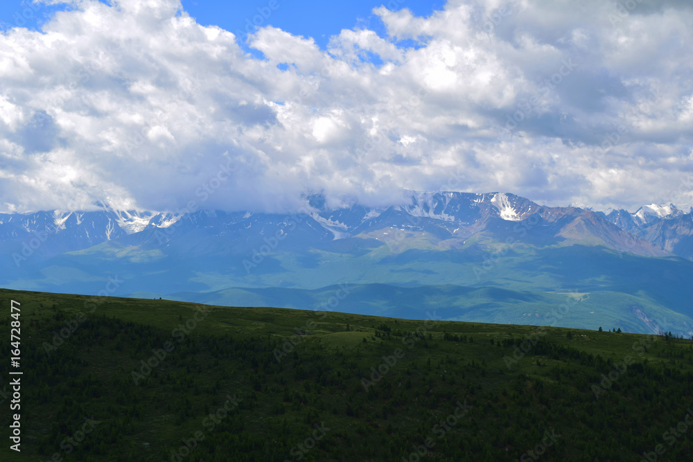 Scenery of North-Chuysky ridge in Altai mountains. Background of big white clouds and forest. Aktash, Altay Region, Siberia, Russia. Scenery of North-Chuysky ridge in Altai mountains. Background of big white clouds and forest. Aktash, Altay Region, Siberia, Russia.