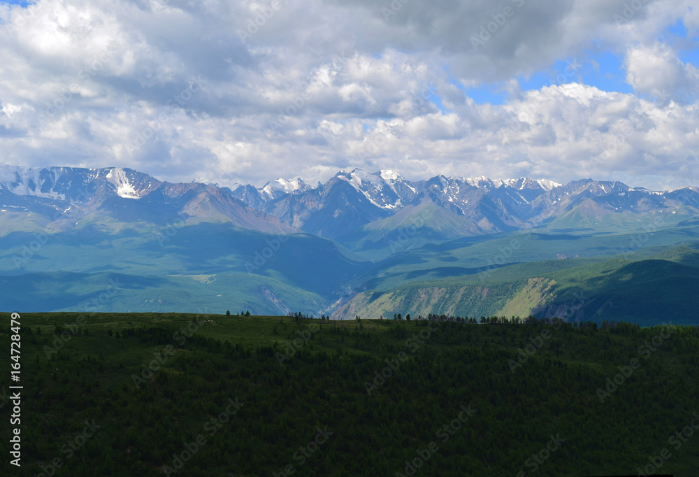 Fototapeta premium View of North-Chuysky ridge in Altai mountains. Background of big white clouds. Aktash, Altay Region, Siberia, Russia.