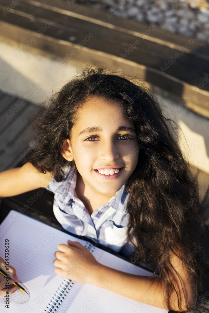 Naklejka premium A Little beautiful girl draws heart in park