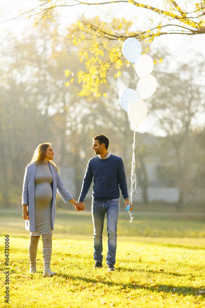 Obraz premium Young couple expecting baby and have fun in the park