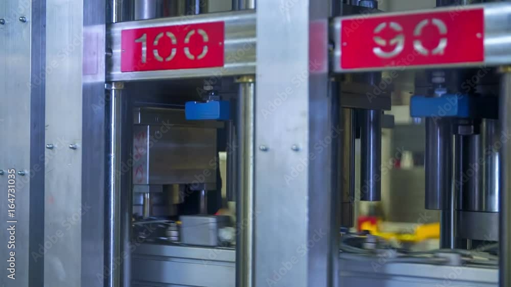 Automatic machinery is slowly moving down towards the items that are travelling down a conveyor belt. Automatic machinery is slowly moving down towards the items that are travelling down a conveyor belt.