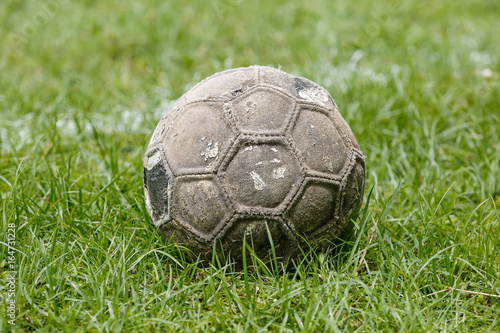 Old used football or soccer ball on field. © toa555