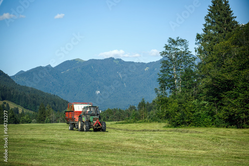Old tractor on meadow. Beautiful mountain view in the Alps photo