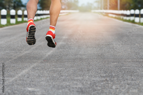 Young fitness man runner legs running on road