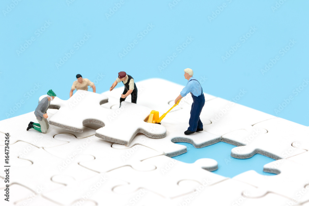 Group of miniature people assembling jigsaw puzzle, team support and help concept. Business teamwork concept. Group of miniature people assembling jigsaw puzzle, team support and help concept. Business teamwork concept.