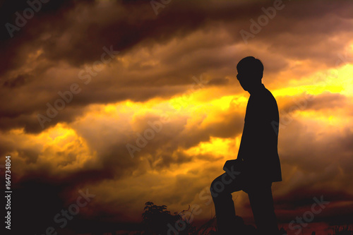Silhouette of young man standing.on sunset.