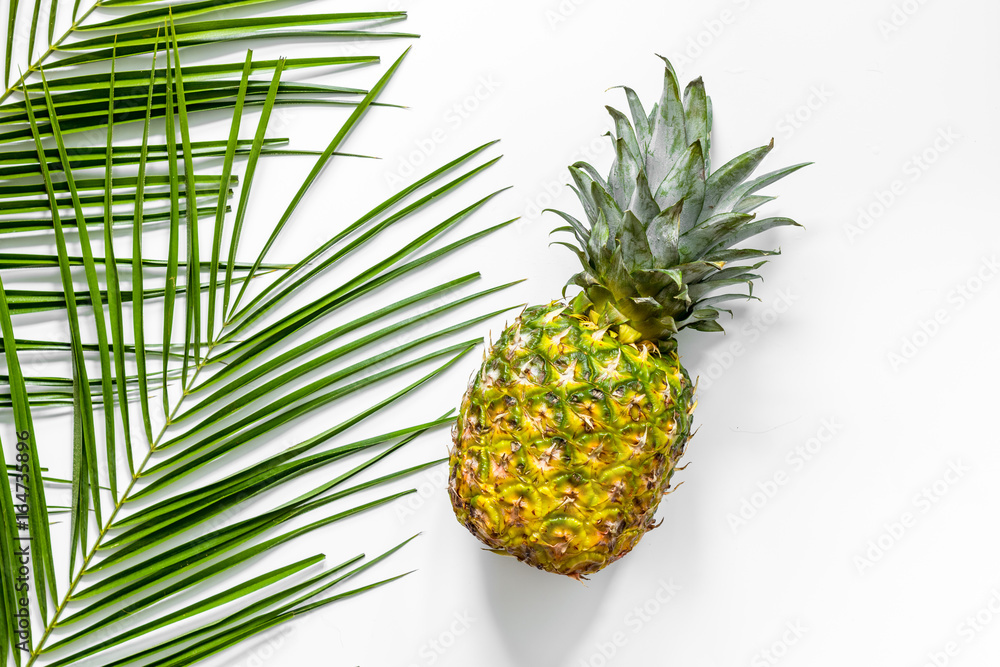 Fototapeta premium Pineapple and palm branch on white background top view copyspace
