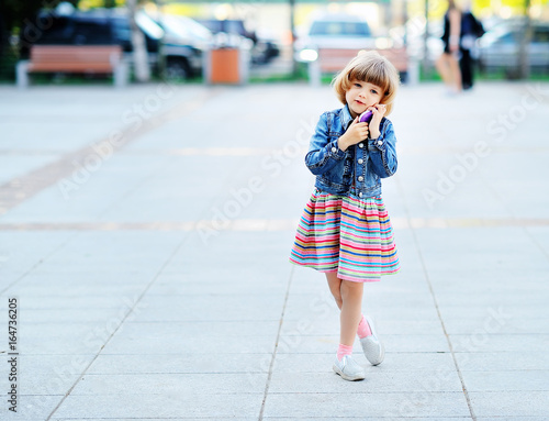 Little girl on the street talking on the toy phone