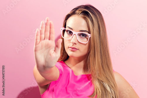 Young woman making a rejection pose on a pink background
