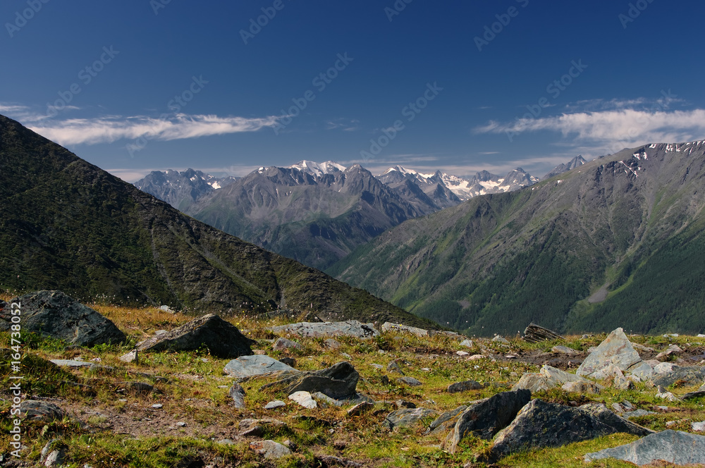 Mountain valley on the background of ranges and snow peaks view from above top height with rocks and alpine meadow in the foreground  Altai Mountains Siberia, Russia