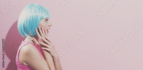 Portrait of a woman in a bright blue wig on a pink background