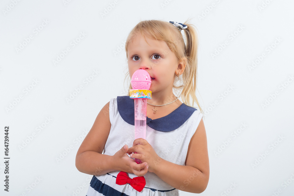 A little girl is singing a cheerful song into the microphone. Happy carefree childhood. A little girl is singing a cheerful song into the microphone. Happy carefree childhood.