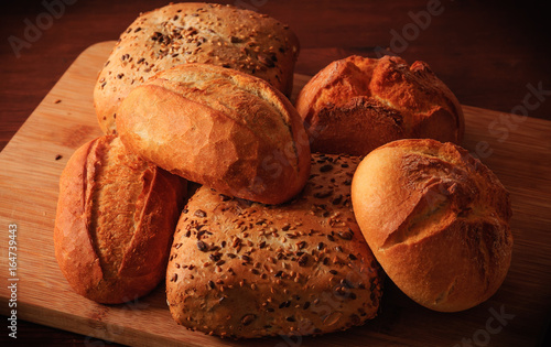 Wheat rolls and multigrain rolls on a wooden board and a brown table